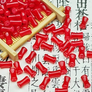 Close-up of red drum-shaped glass beads on bamboo tray for DIY jewelry making crafts