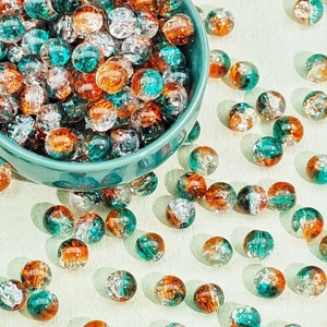 Macro detail of 8mm Christmas crackle glass beads in orange and teal for DIY jewelry