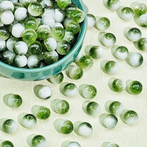 Detail of green and white cracked glass beads in a ceramic bowl for DIY jewelry making