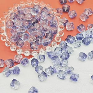 Macro shot of purple gradient irregular faceted glass beads in a vintage glass tray