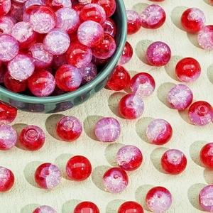 Detail of red and purple crackle glass beads in a green bowl for DIY jewelry making