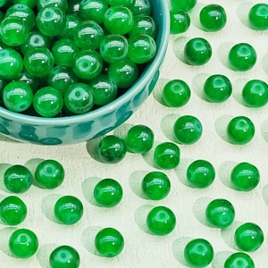 Macro shot of green glass beads in a ceramic bowl for DIY jewelry and necklaces