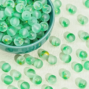 Macro detail of mint green frosted glass beads with gold foil for DIY jewelry making