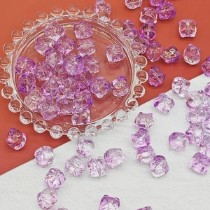 Macro shot of purple faceted resin beads with gold leaf foil inside on a glass plate