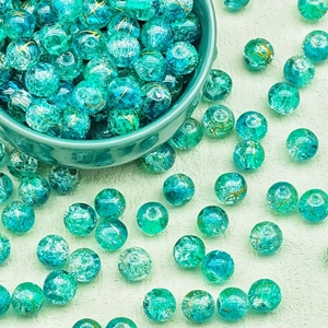 Close-up of translucent emerald green glass beads with decorative gold crackle textures
