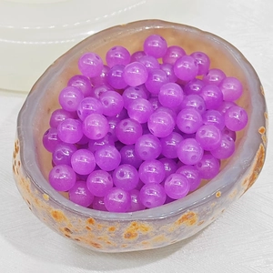 Macro shot of purple chalcedony glass beads in a natural stone bowl for jewelry making