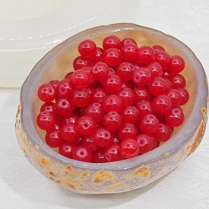 Close-up of translucent red glass beads for DIY jewelry making in a stone bowl
