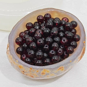 Macro shot of 4-8mm deep red translucent glass beads in a jade chalcedony bowl