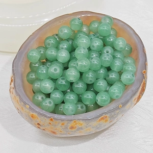 Macro shot of polished green aventurine round beads in a natural stone bowl