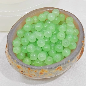 Close-up of translucent light green chalcedony glass beads in a textured stone bowl