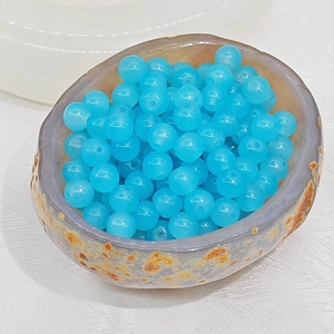 Macro shot of bright blue translucent round beads with smooth finish and central hole for DIY