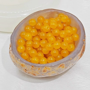 Close-up of translucent orange carnelian glass beads in a stone textured bowl