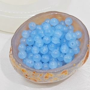 Macro shot of transparent light blue glass beads with pre-drilled holes in a stone bowl