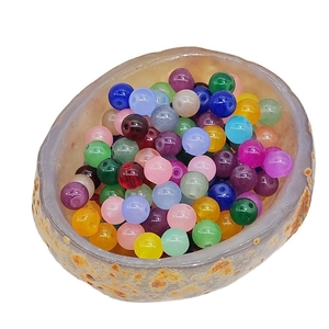 Vibrant translucent colorful round beads in a natural stone bowl for DIY jewelry making