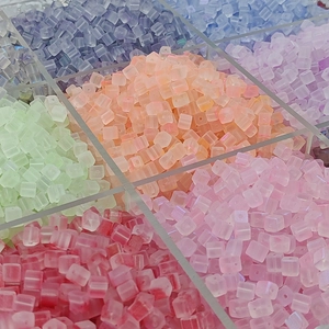 Vue macro de perles en verre givré 7mm couleurs macaron dans une boîte de rangement