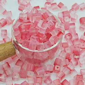 Gros plan de perles cubiques roses dépolies de 7 mm en verre pour la création de bijoux