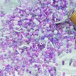 Detailed view of assorted purple DIY glass seed beads and tubes for jewelry making