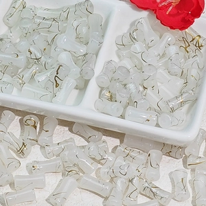 Macro detail of 12x6mm white bamboo joint glass beads with golden wave texture for DIY jewelry