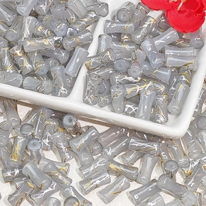 Macro view of gray bamboo-shaped glass beads with gold sand texture for DIY jewelry