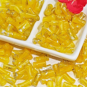 Macro detail of 6x12mm yellow bamboo-shaped glass beads with fine silk texture patterns