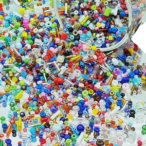 Colorful DIY glass seed beads and bugle beads assortment for jewelry making on white surface