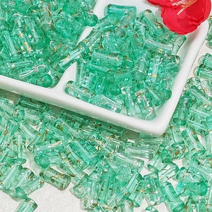Macro shot of 12x6mm bamboo-style green glass beads with gold texture for DIY jewelry