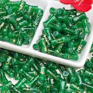 Detailed macro view of dark green bamboo shaped glass beads with golden cracked texture