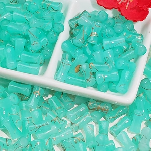 Close-up of bamboo-shaped glass beads with gold texture in a white ceramic dish