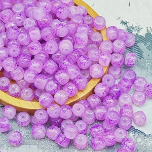 Dettaglio di perle di vetro viola con motivo e foro centrale per la creazione di gioielli
