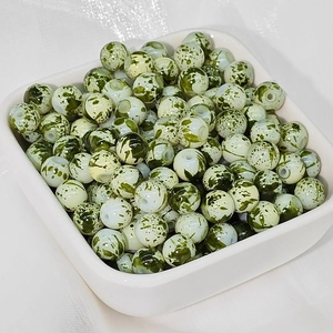 Dettaglio macro di perle in ceramica da 8mm con motivo marmorizzato verde e bianco