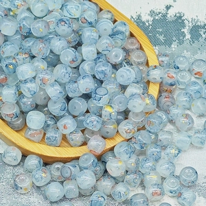 Dettaglio di perle di vetro blu chiaro dipinte a inchiostro per creazione gioielli DIY