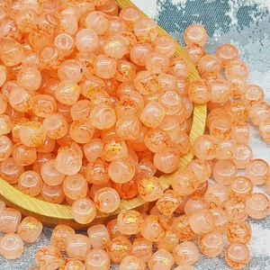 Dettaglio macro di perle in vetro pesca con motivo craquelé e intarsio in foglia d'oro