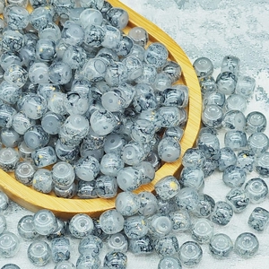Dettaglio di perle in vetro marmorizzato 6x8mm con pagliuzze dorate su vassoio