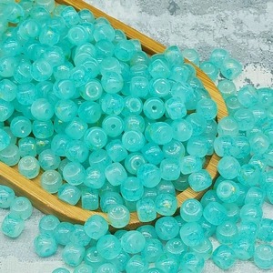 Dettaglio di perle in vetro azzurro con venature dorate su un vassoio di bambù