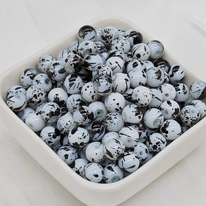 Dettaglio di perle in ceramica bianca con schizzi di inchiostro nero nel vassoio