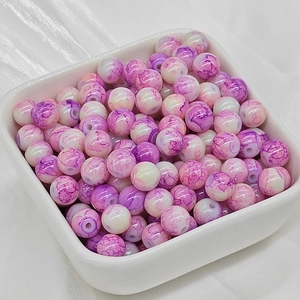 Dettaglio macro di perle in ceramica marmorizzata viola e bianca in una ciotolina bianca