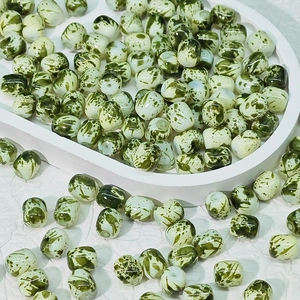 Gros plan de perles en céramique peintes à l'encre verte et blanche pour bijoux DIY