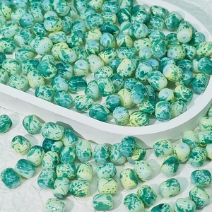 Gros plan de perles cylindriques DIY avec motifs marbrés vert et jaune pour bijoux