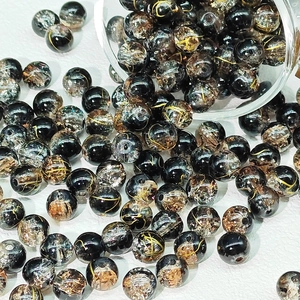 Vista macro di perle in vetro nero e oro da 8-10mm con trama ghiaccio per fai da te