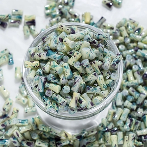 Détail de perles cylindriques en céramique peintes avec effet d'encre vert et violet