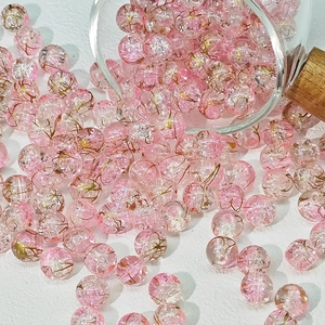 Dettaglio macro di perle di vetro crackle rosa da 10mm con foglia d'oro per gioielli
