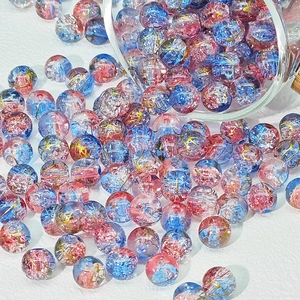 Dettaglio di perle in vetro craquelé rosa e blu con fili dorati per gioielli fai da te