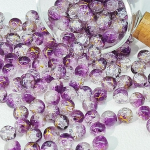 Vista macro di perline di vetro crepate viola da 10mm con seta dorata per gioielli DIY
