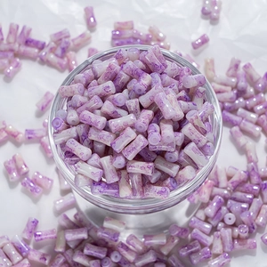 Détail de perles en porcelaine violette marbrée avec effet lavis dans un bol en verre