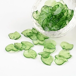 Detailed view of green acrylic leaf beads with veins and holes for DIY jewelry making
