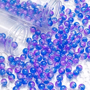 Macro shot of 10mm blue and purple ice-crackle glass beads falling from clear storage tubes