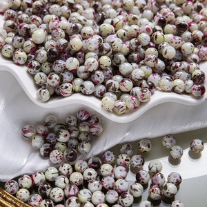 Vue détaillée de perles en céramique peintes avec motifs éclaboussures pour bijoux DIY