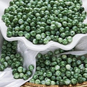 Vue macro de perles rondes en verre à texture marbrée verte pour la création de bijoux