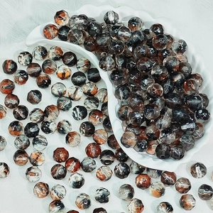 Detail of 10mm faceted glass beads with marble texture in a ceramic crescent tray