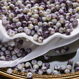Détail de perles en céramique marbrées violet et crème pour la création de bijoux